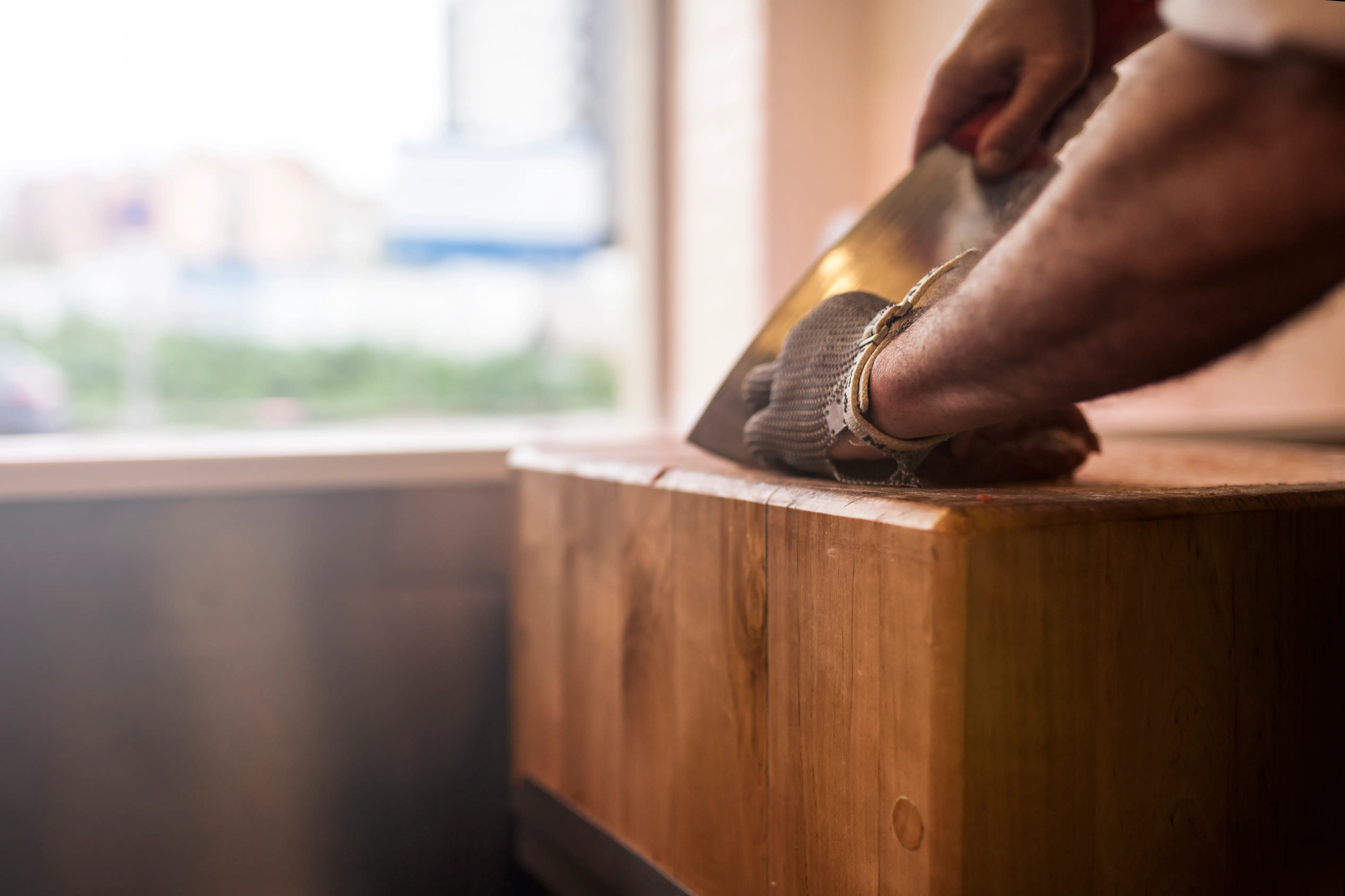 close up carpenter sanding down wood