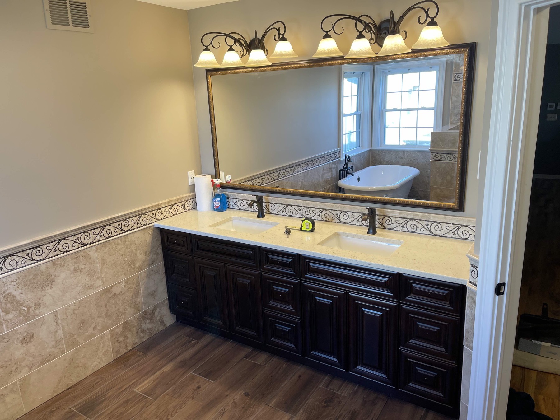 Double vanity in a Stewartsville, NJ bathroom with dark raised-panel cabinets, a light quartz countertop, two undermount sinks and a framed mirror above a mosaic tile backsplash