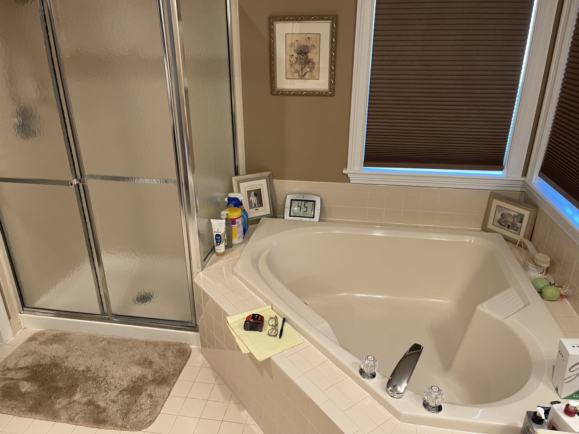 Dated beige corner jacuzzi tub and framed shower enclosure with beige tile surround in a Stewartsville, NJ bathroom before renovation