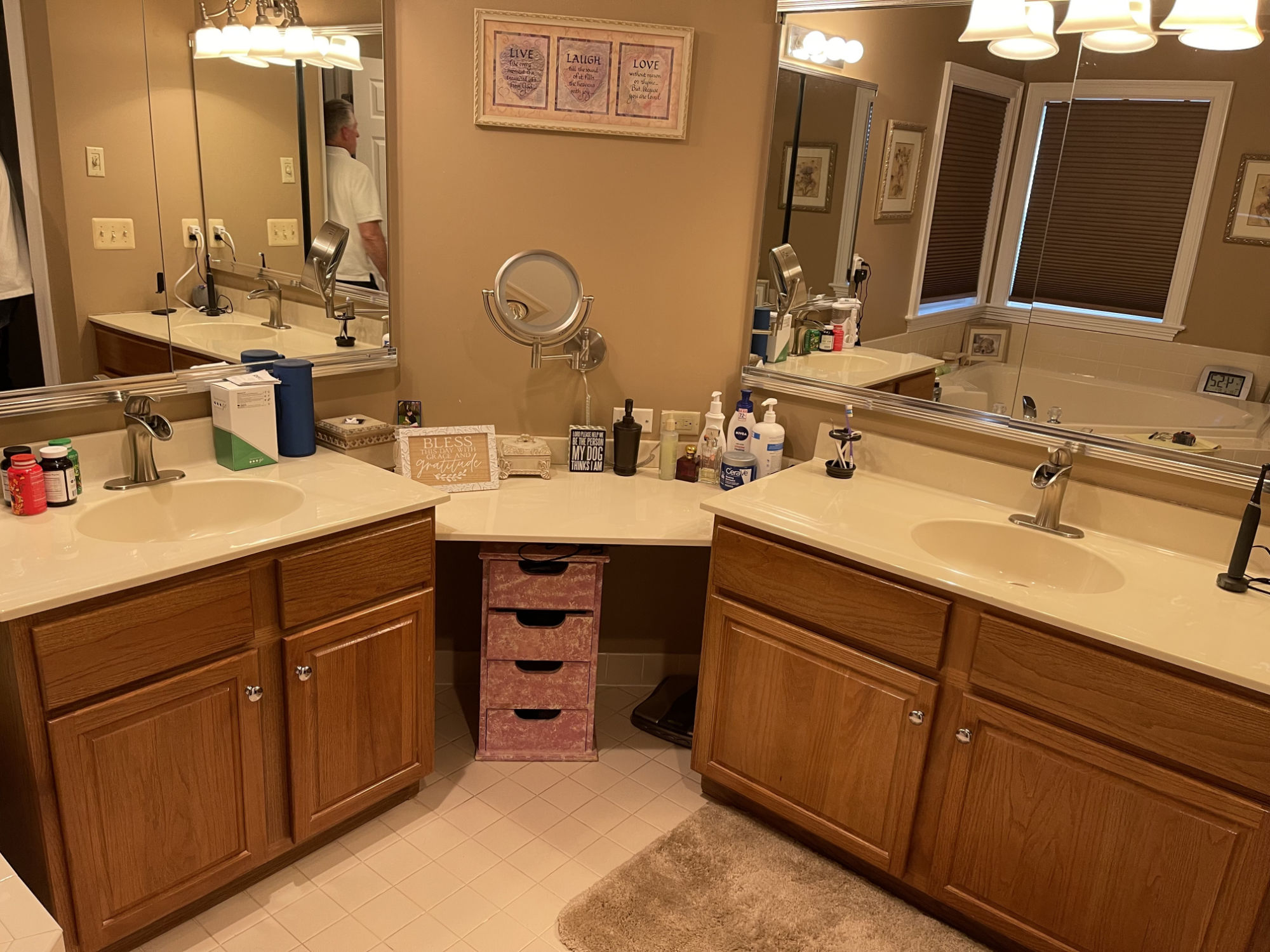 Dated oak double vanity with a cultured marble top, brass-trimmed mirrors and beige tile floor in a Stewartsville, NJ bathroom before renovation