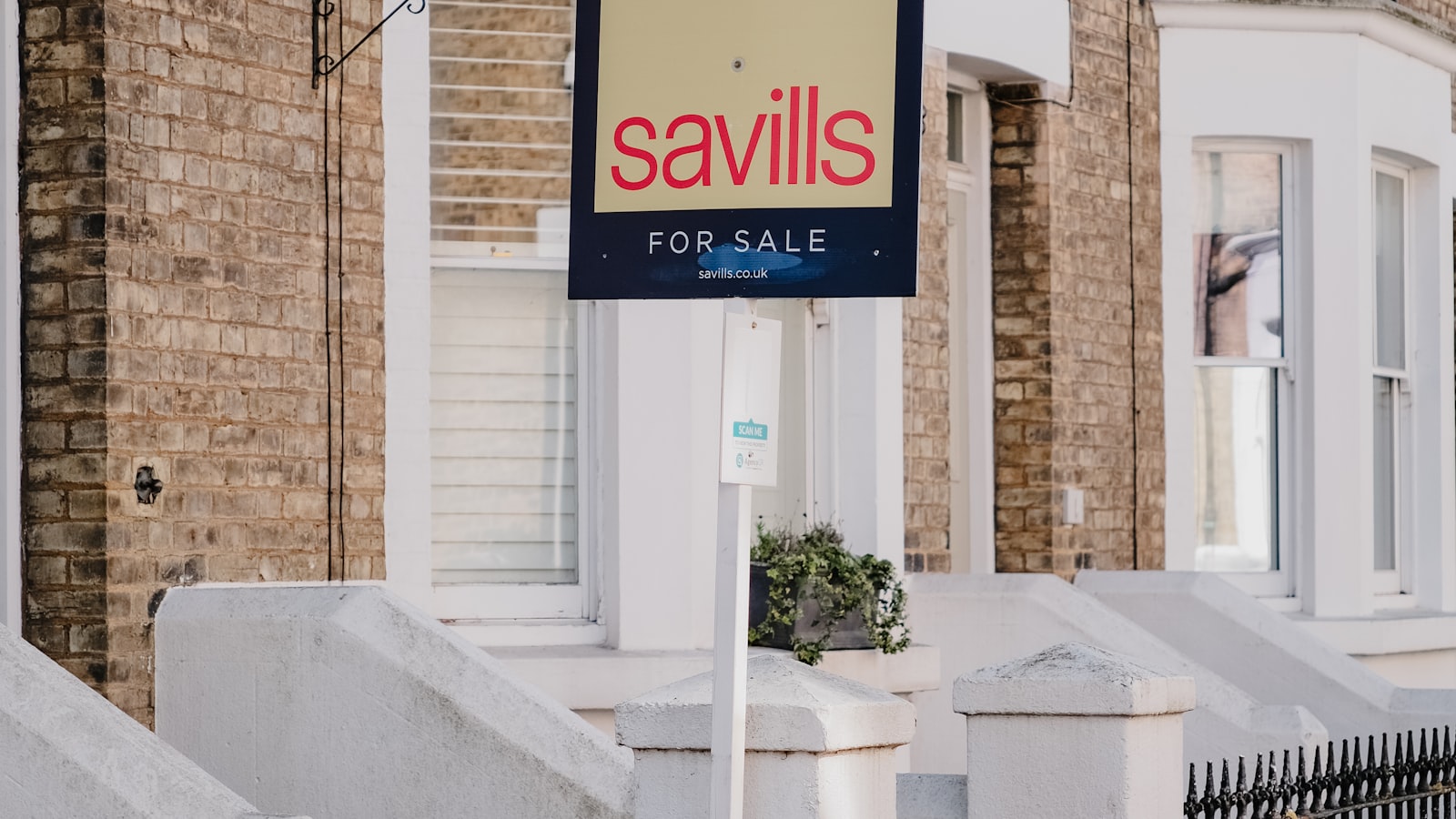 A for sale sign outside UK townhouses