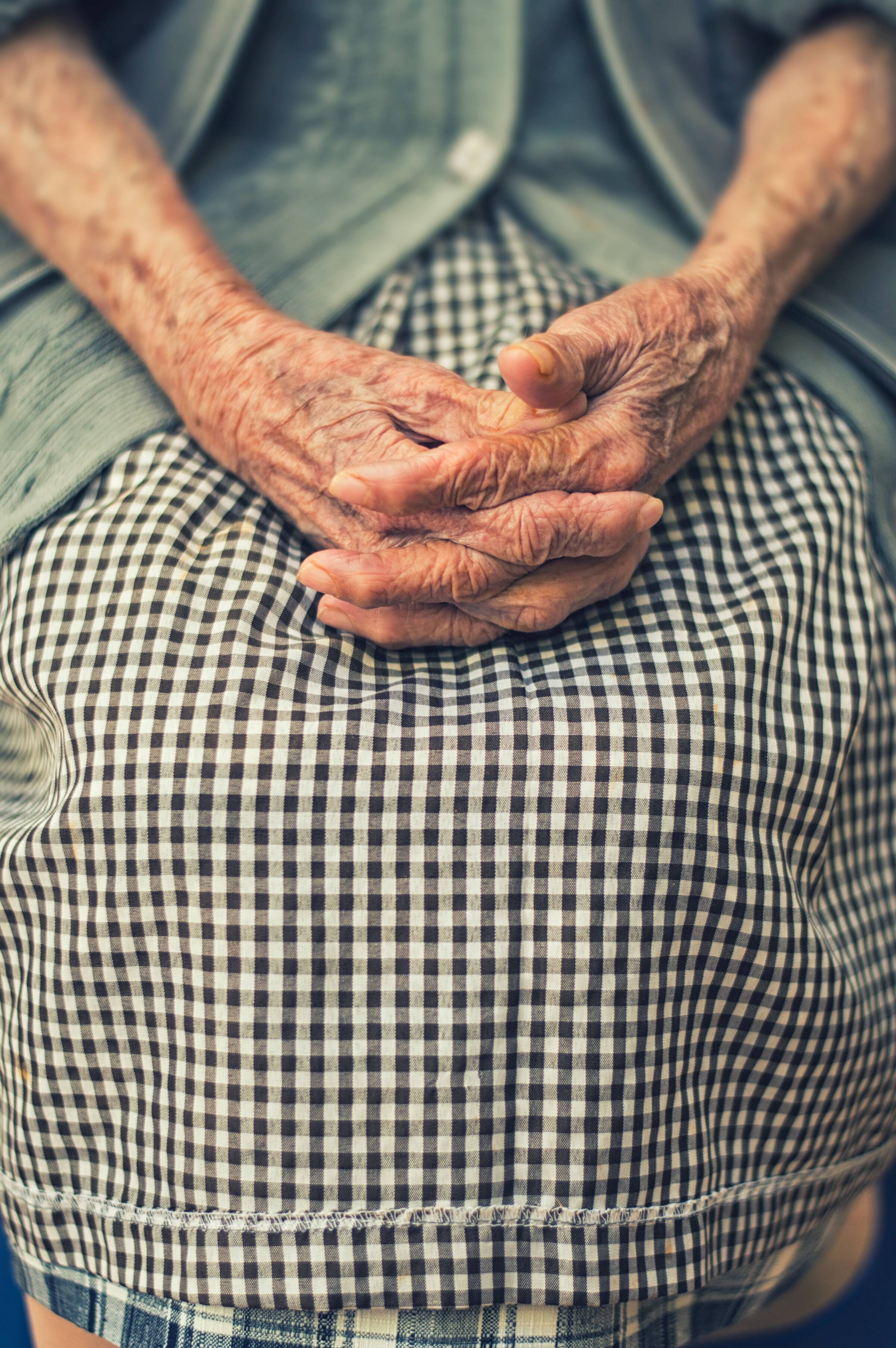 An older person's hands clasped in their lap