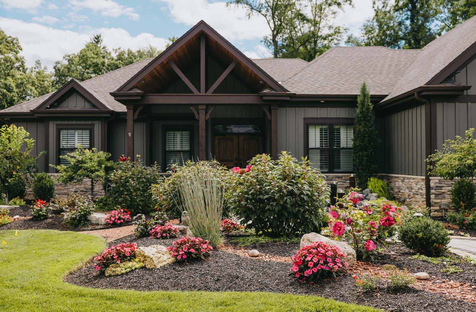 Front yard with layered flower gardens, stone accents, and manicured landscaping at a Chicago suburban home.