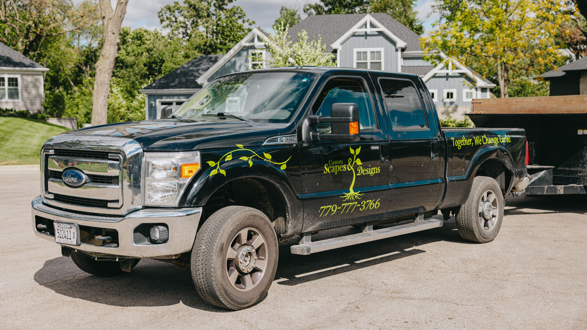 Custom Scapes and Designs landscaping truck with company logo and phone number parked in a residential neighborhood in the Chicago suburbs.