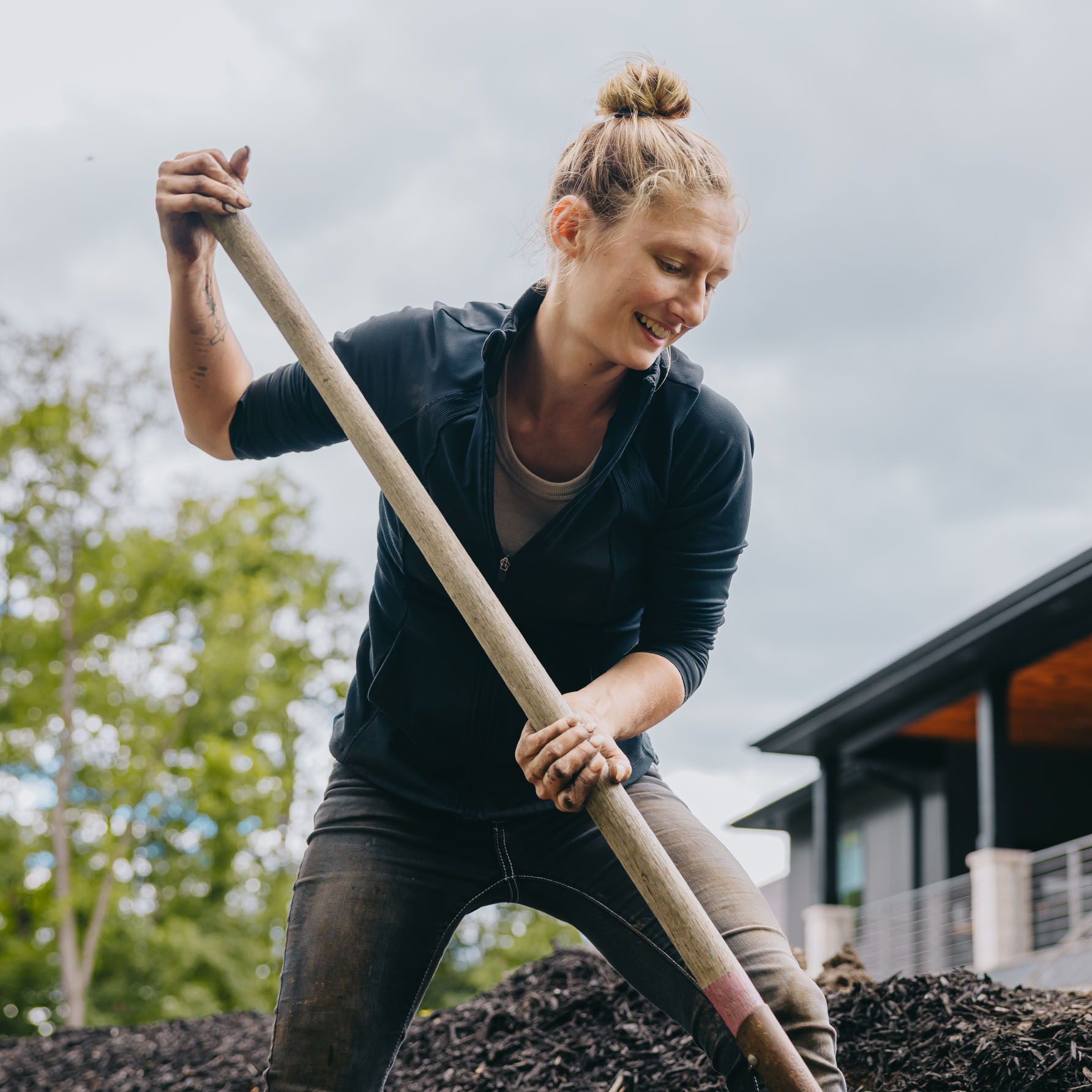 Female landscaper working with shovel to move mulch for a landscape installation in suburban Chicago.