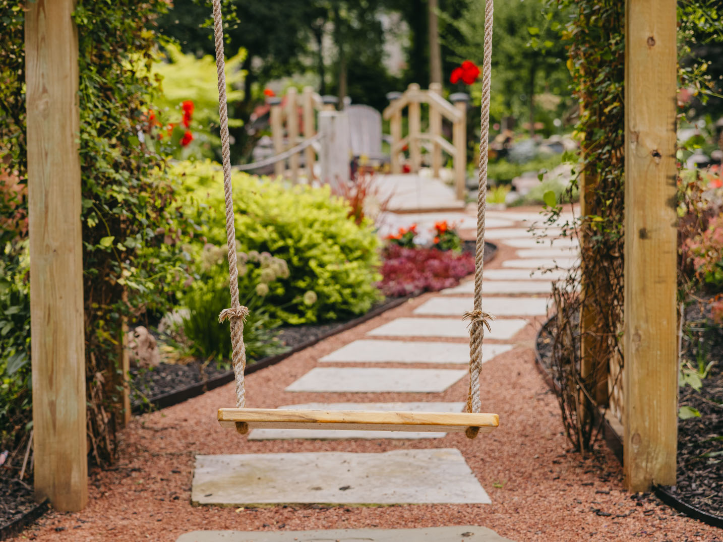 Wooden garden swing along stone path in a landscaped backyard, Chicago suburbs.