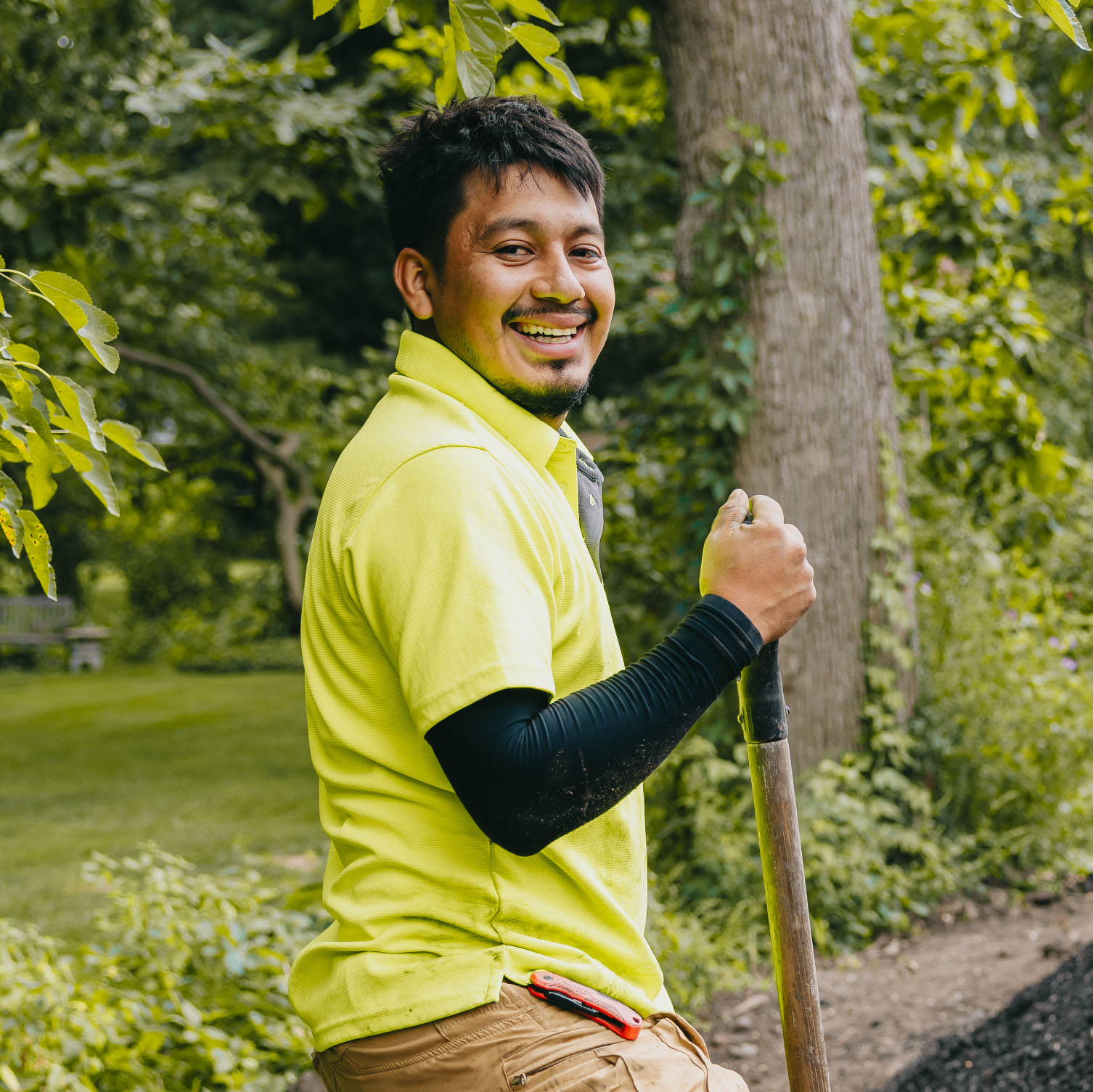 Smiling landscape worker holding a shovel during a residential garden project in the Chicago suburbs.