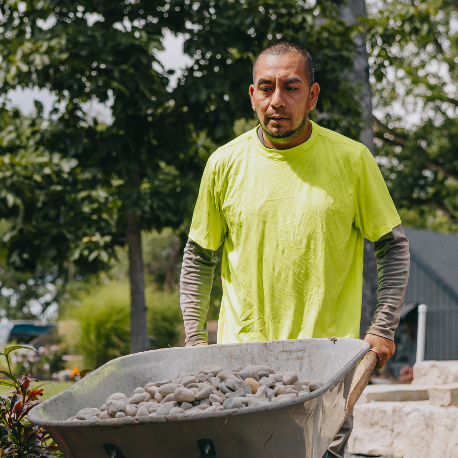 Close-up of landscaper transporting wheelbarrow full of stones for backyard project, Chicago suburbs.