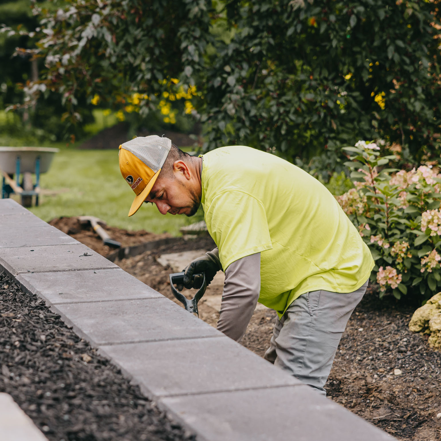 Landscape technician installing stone edging along garden bed in a suburban Chicago yard.