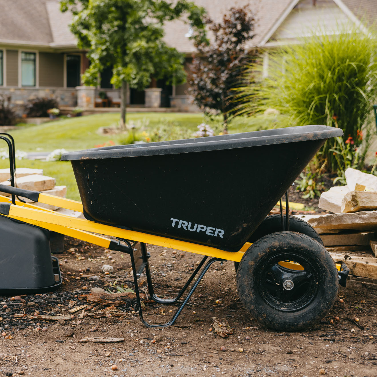 Black and yellow wheelbarrow positioned at residential landscaping project site