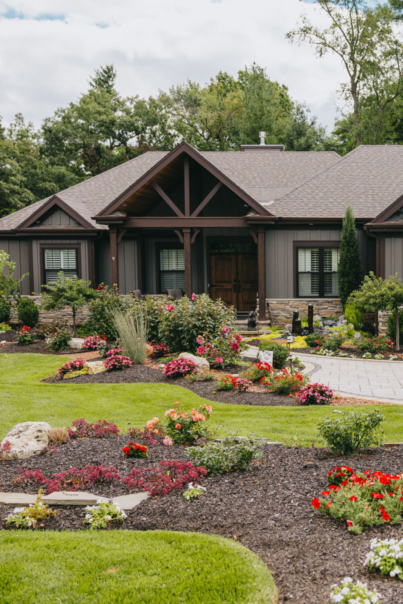 Elegant front yard with layered flower beds, fresh mulch, and manicured edges