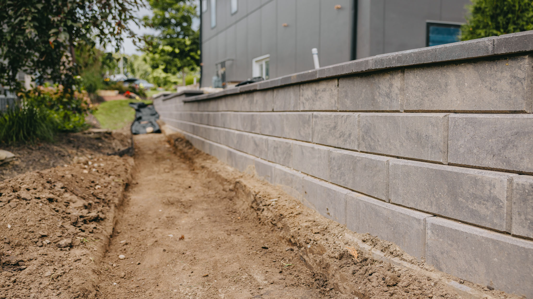 Retaining wall construction in progress showing soil grading and stonework details