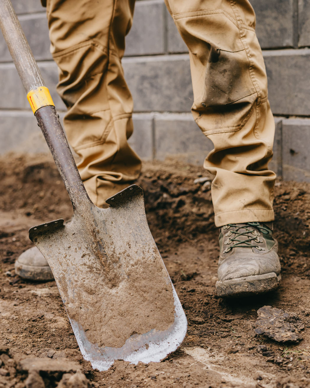 Landscape technician digging soil during a Custom Scapes and Designs project in suburban Chicago.