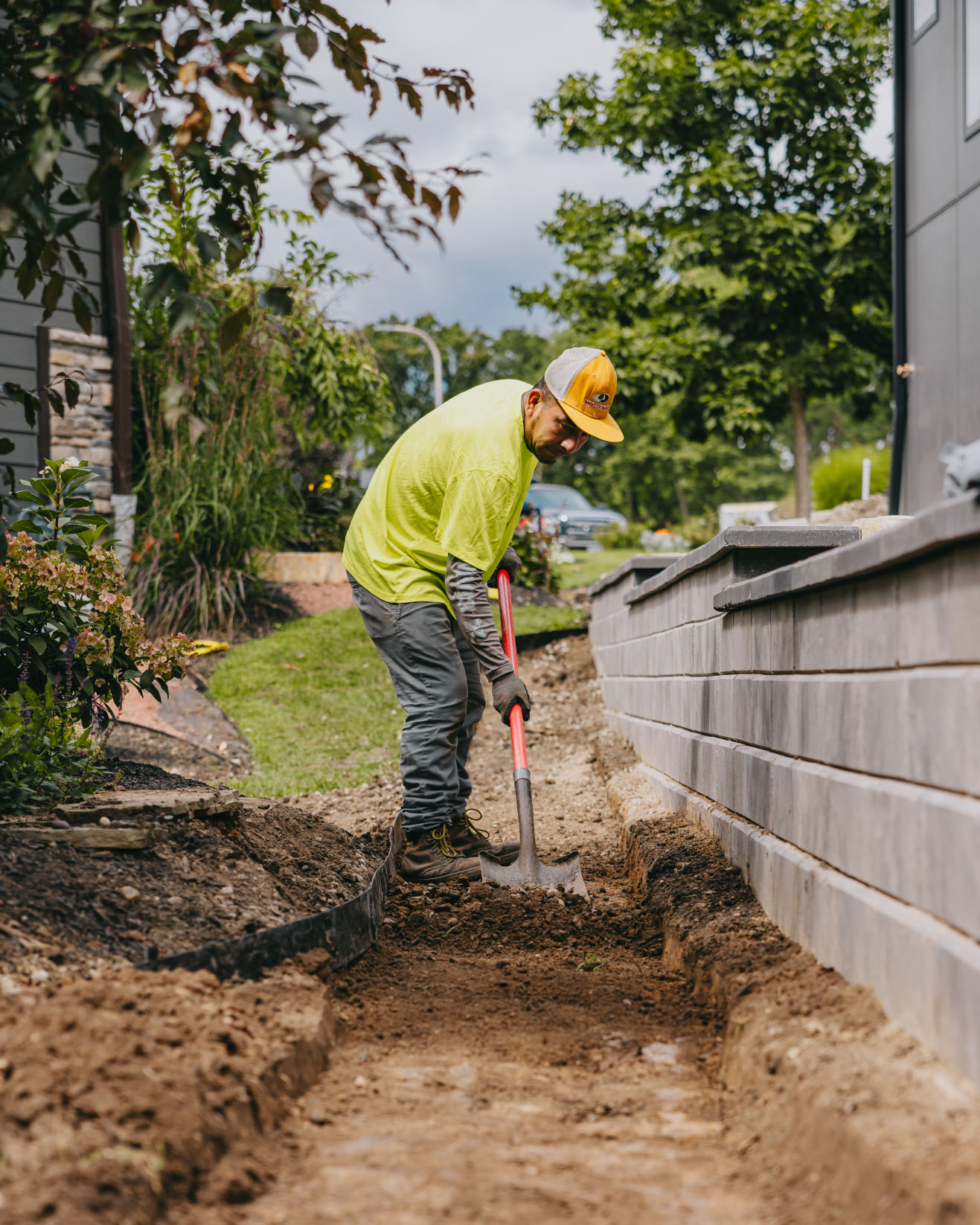 Worker preparing foundation and trench for a retaining wall installation by Custom Scapes and Designs in suburban Chicago.
