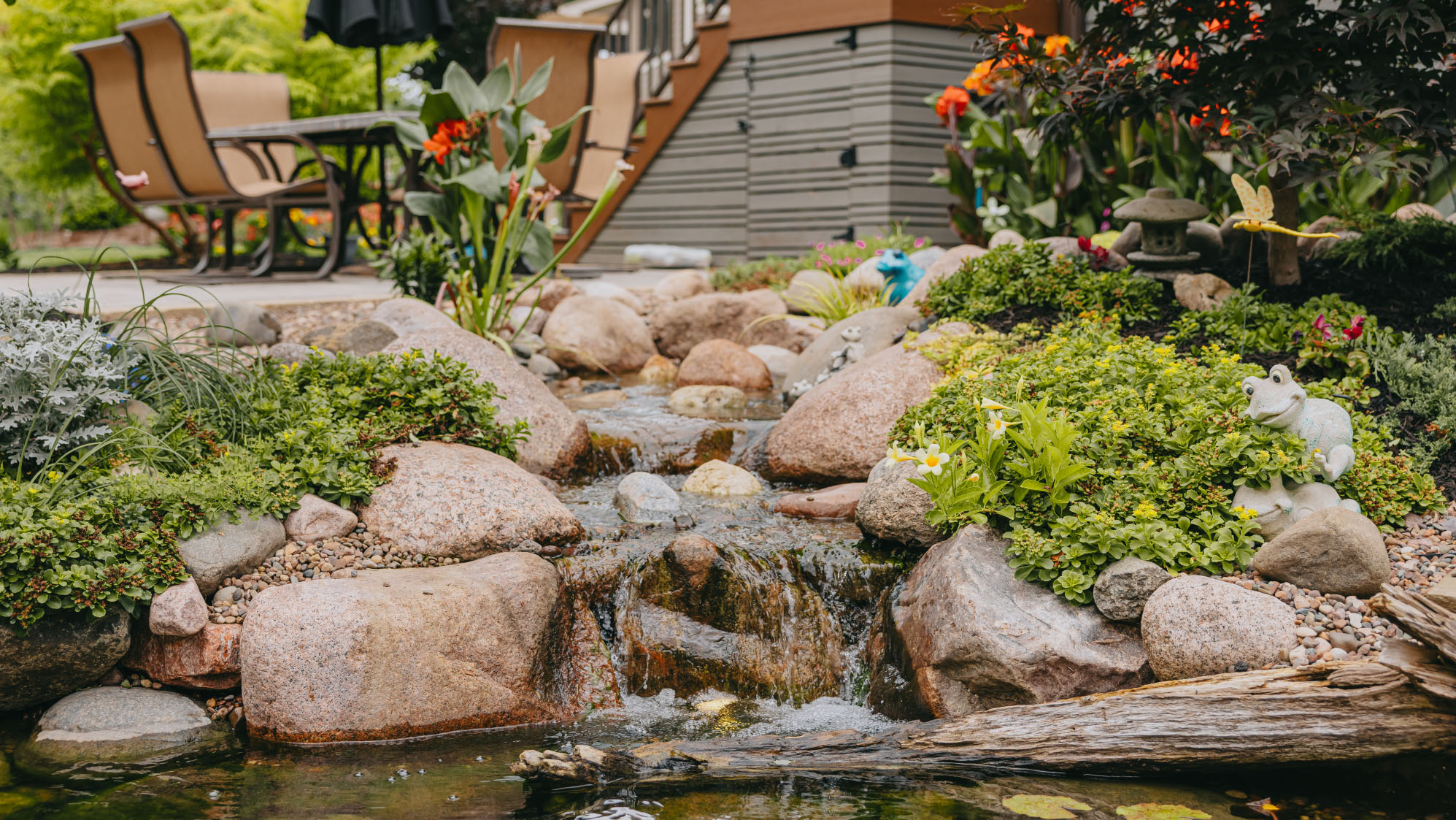 Custom backyard waterfall and pond surrounded by rocks and greenery in a Chicago suburbs landscape design.