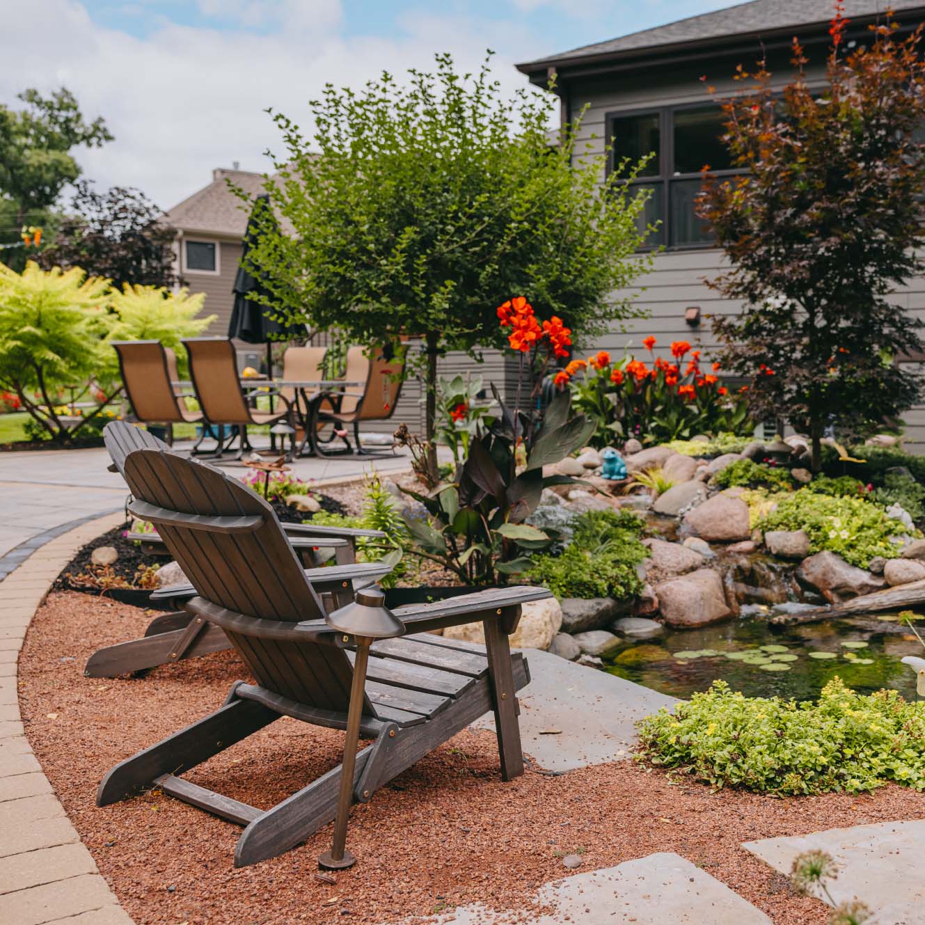 Peaceful garden pond with Adirondack chair and colorful plants in suburban Chicago yard