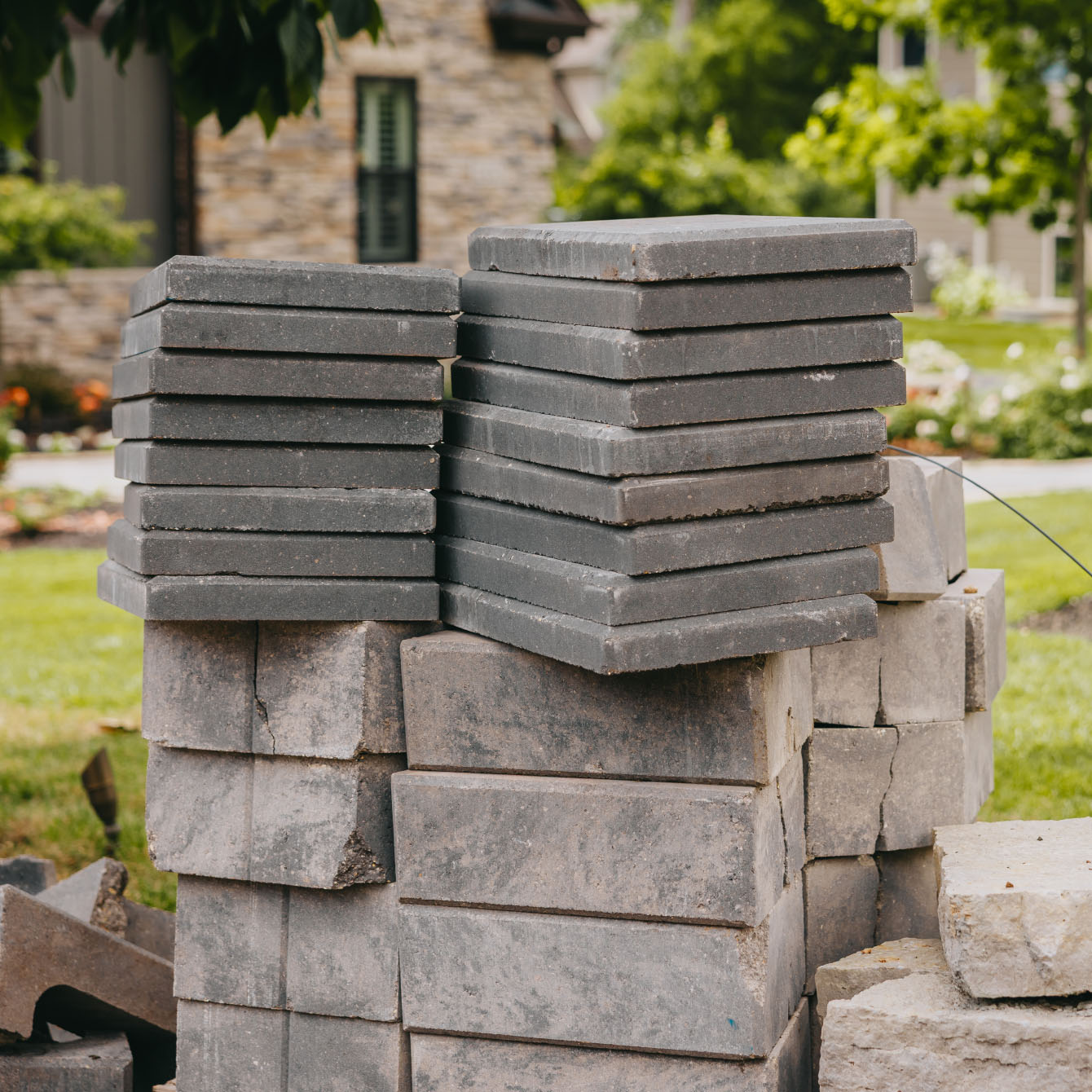 Stack of gray concrete pavers prepared for new patio build in suburban yard
