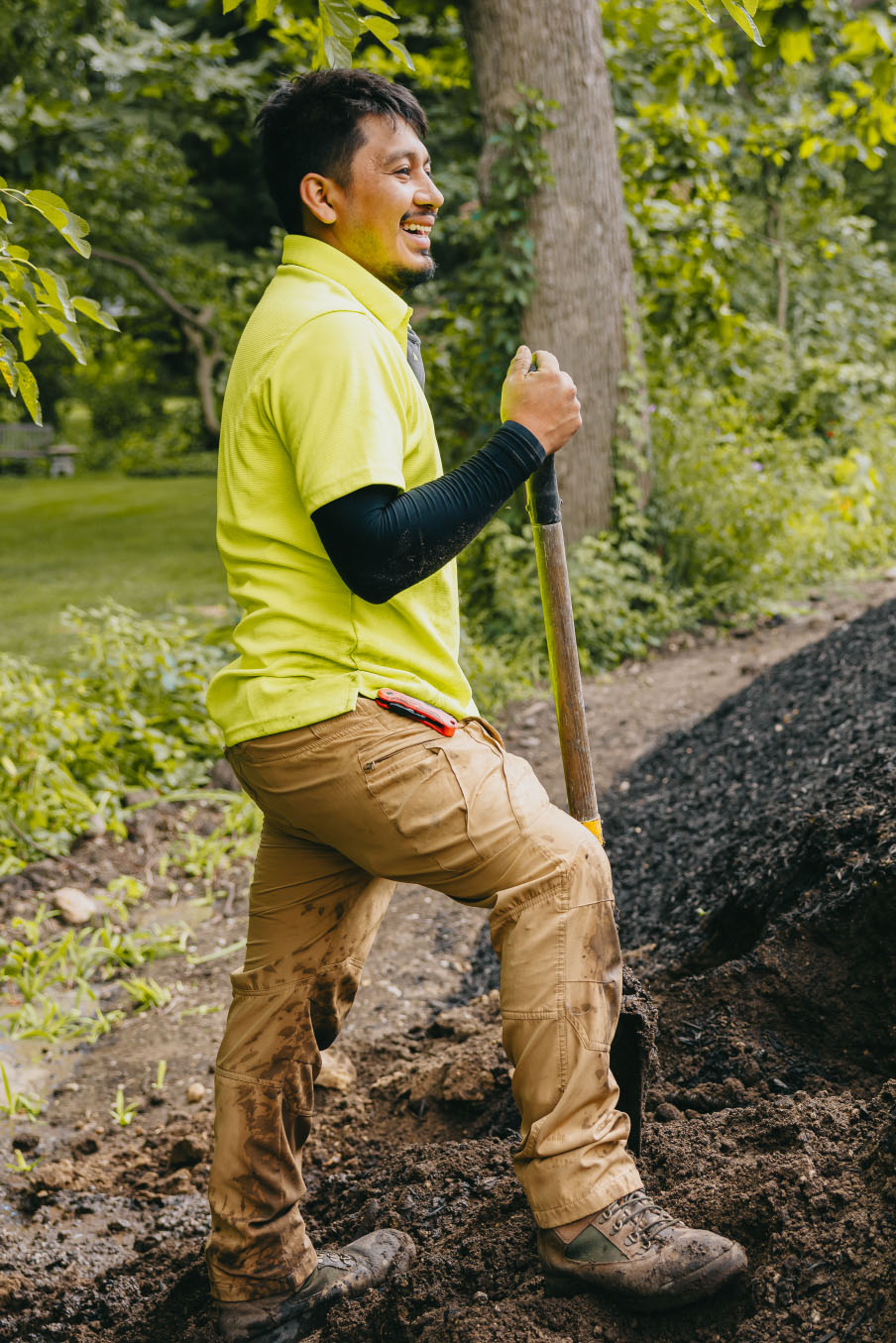 Landscaping crew member smiling while working outdoors during a garden installation