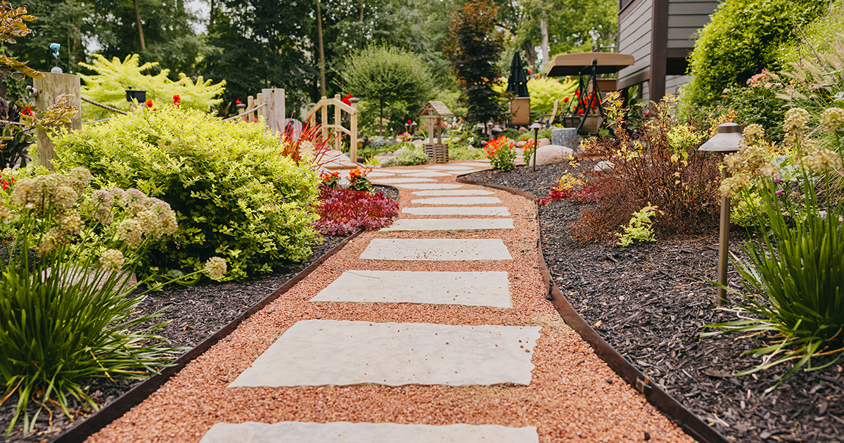 Winding stone garden pathway surrounded by colorful plants and shrubs, showcasing a detailed garden design.