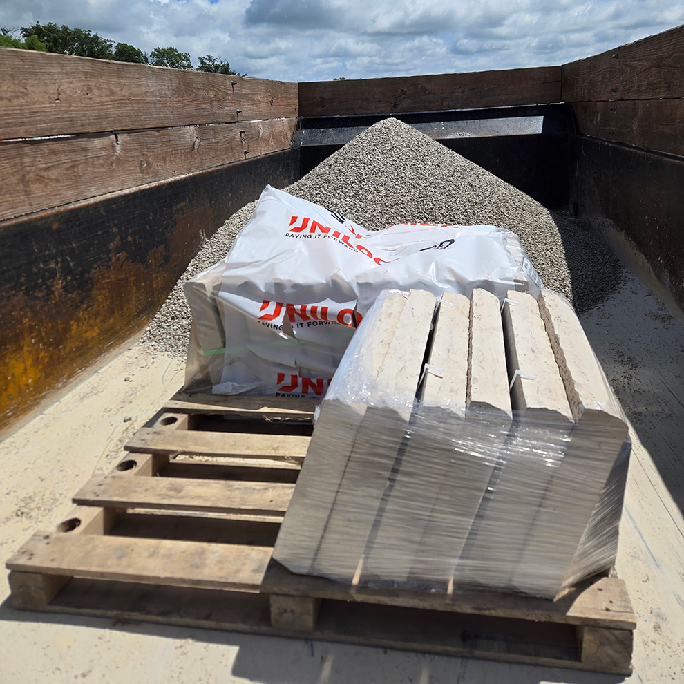 Pallet of landscape materials including bags of gravel and pavers delivered for the Richards residence project.