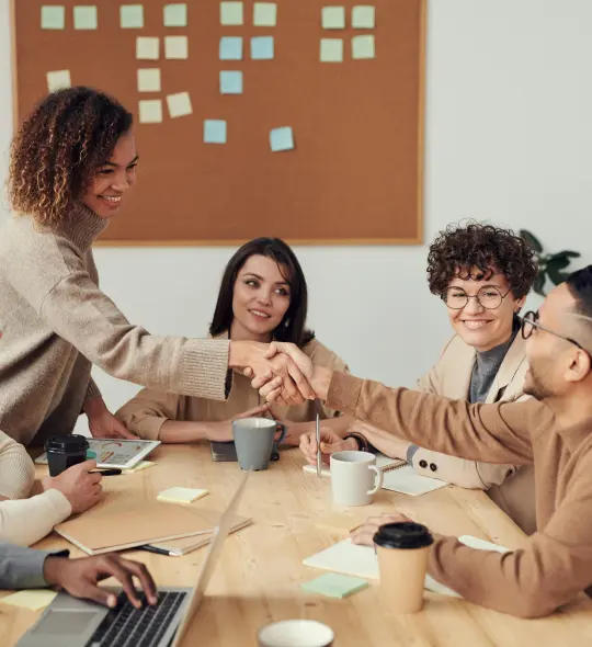 team members smiling and shaking hands in a meeting