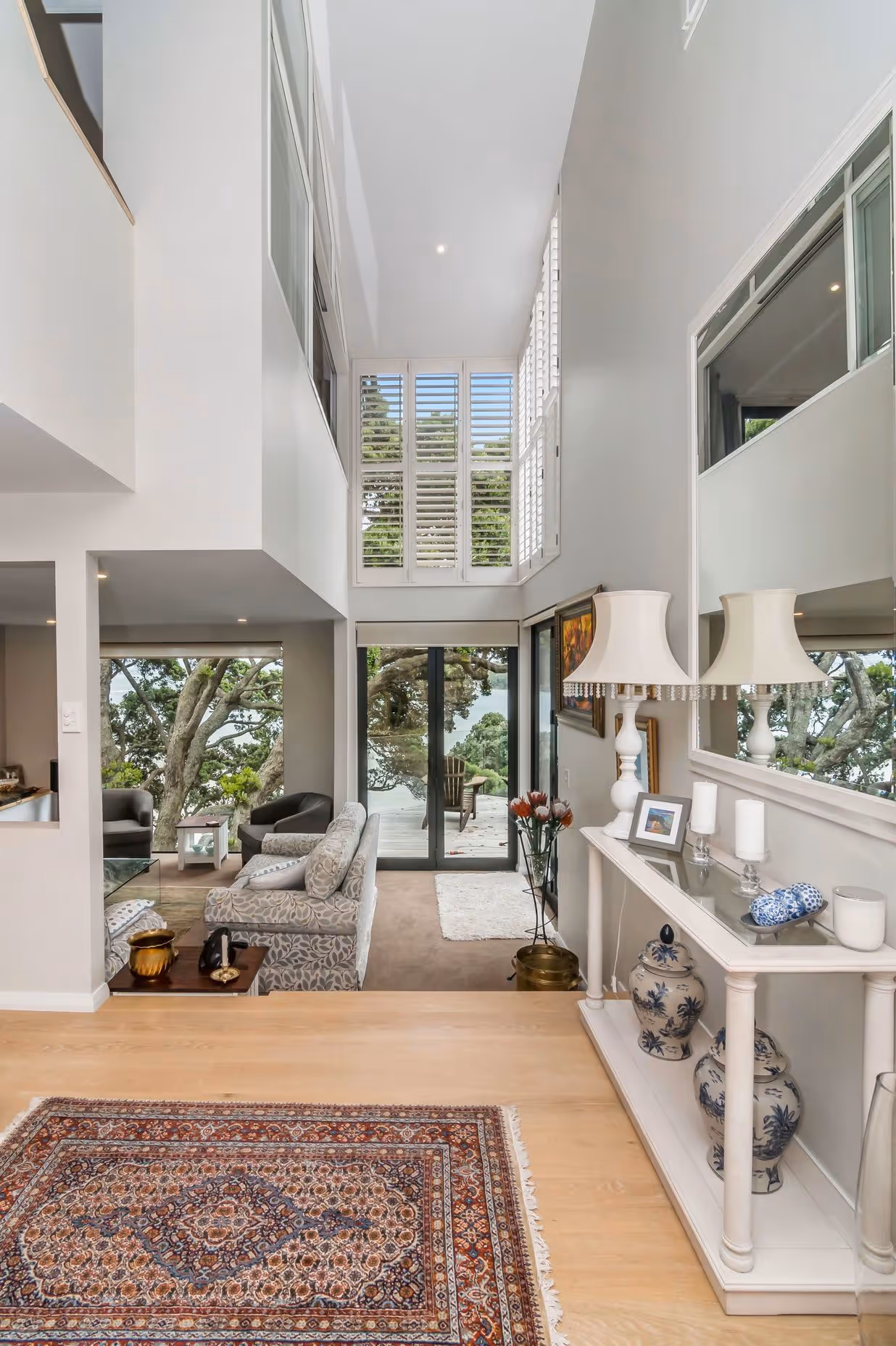 Bright, modern living space with large windows, a cozy sofa, and view of greenery. Elegant decor and natural light create a welcoming atmosphere.