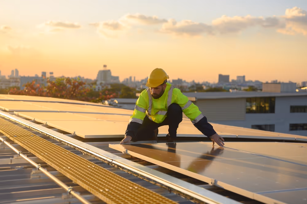 An electrician on a roof installing solar panels