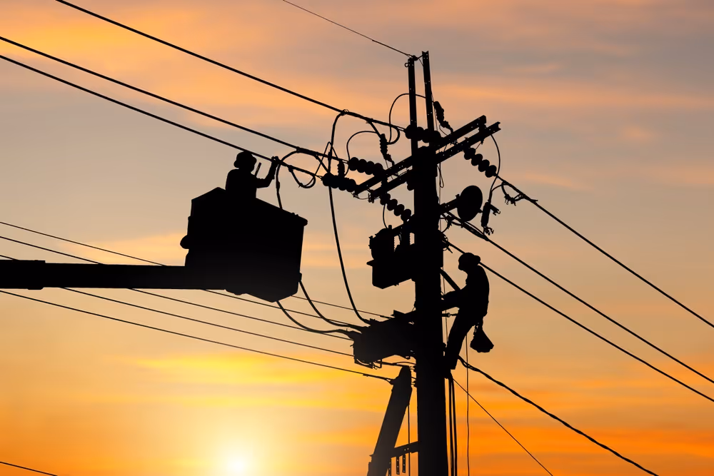 Electrician fixing powerlines in the sunset