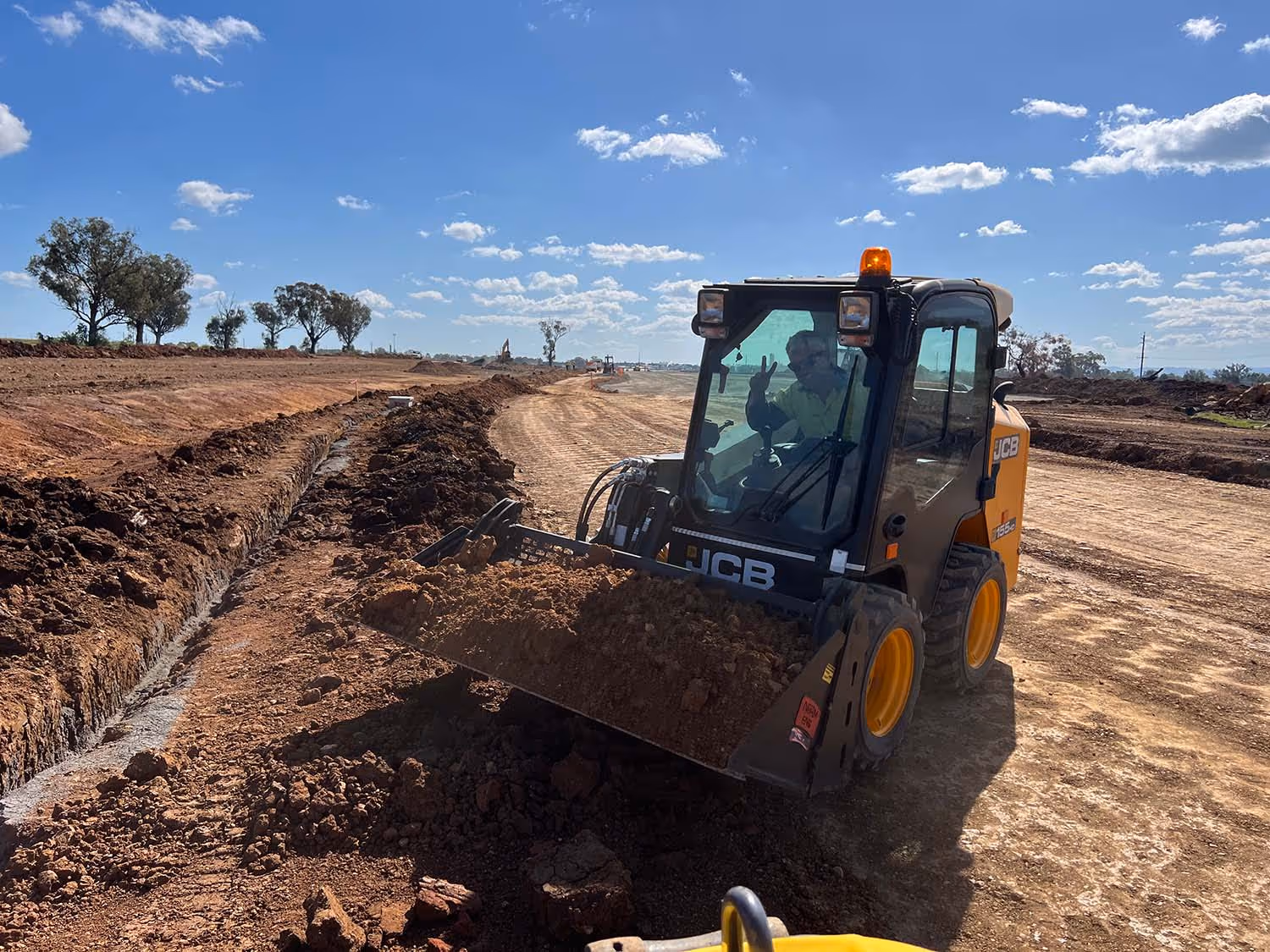 Yellow skid steer moving dirt around on a work site