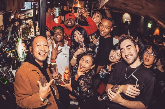 Group of diverse friends smiling and holding drinks at a lively indoor party.