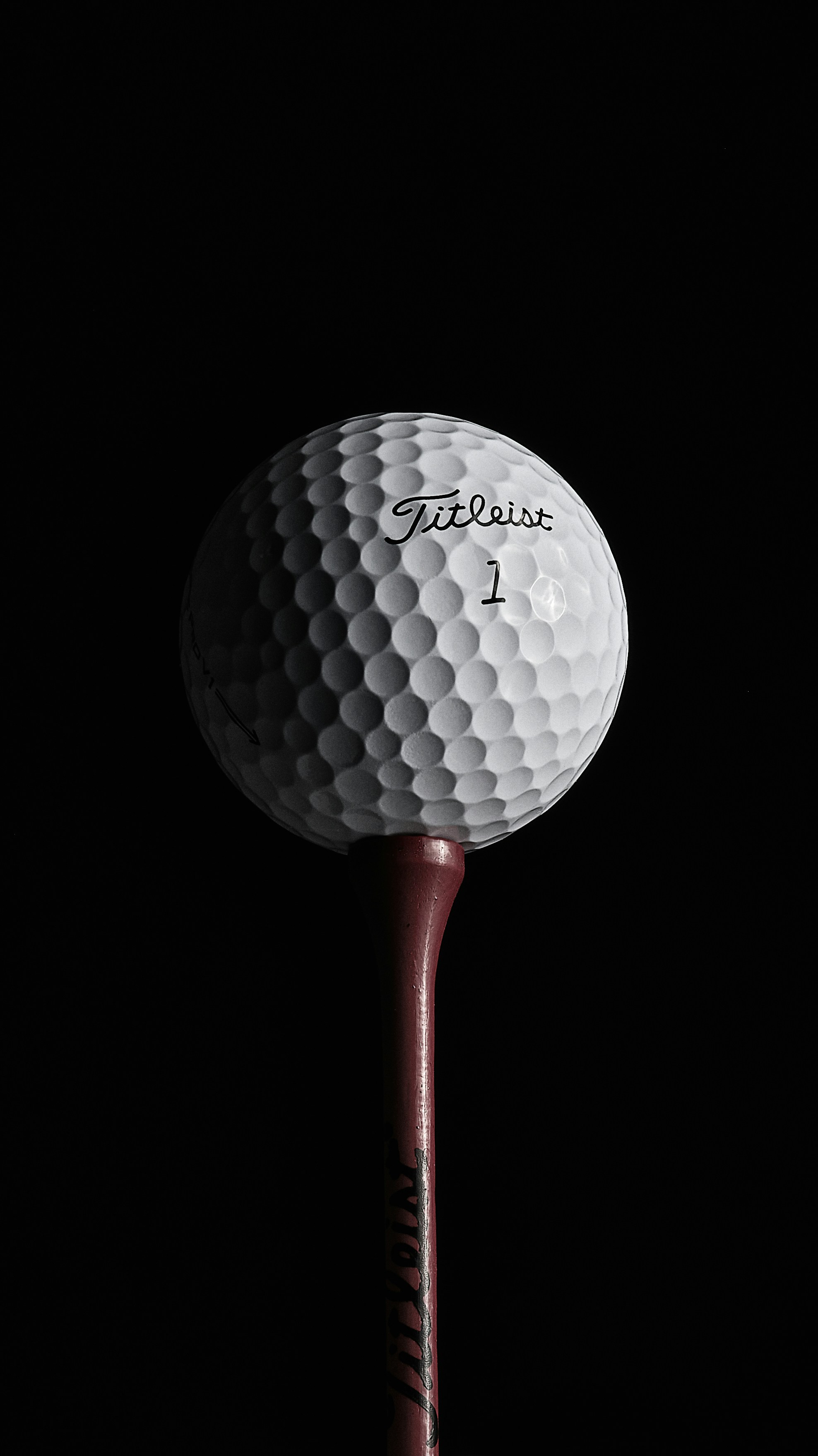 A Titleist golf ball sitting on a wooden golf tee