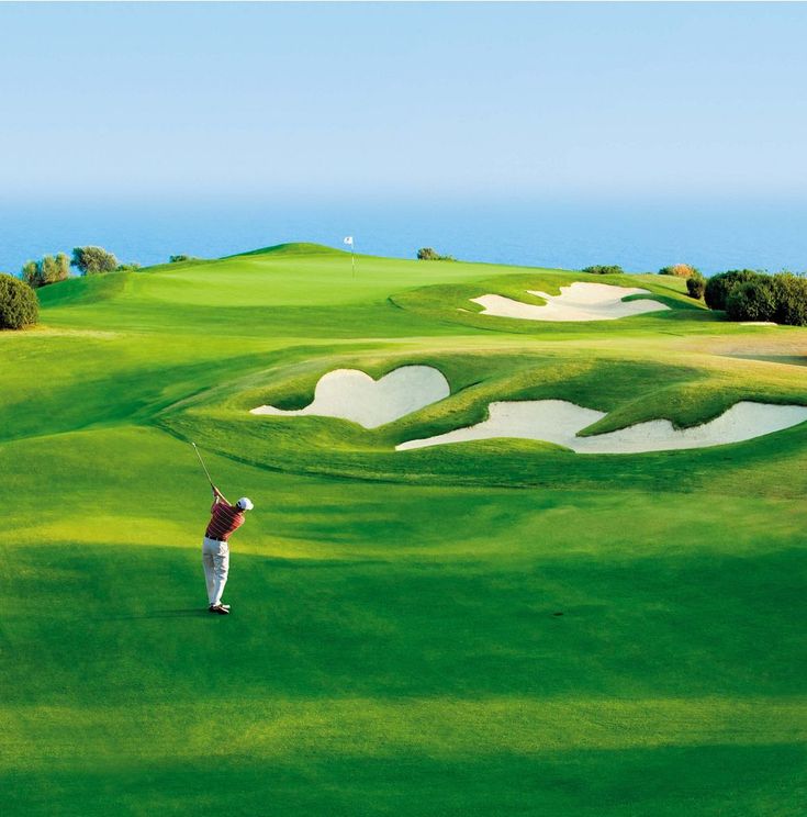 A golfer on a coastal golf course fairway, hitting an approach shot towards the green