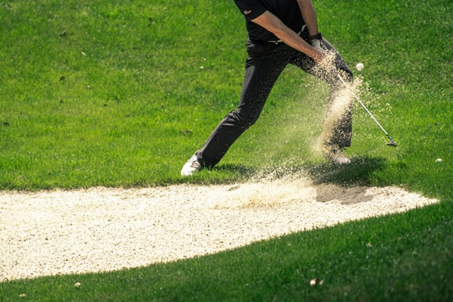 A golfer hitting a bunker shot
