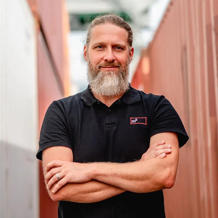 CEO von m3 posiert vor einem Container