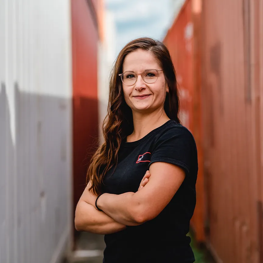 Mitarbeiterin posiert vor einem Container