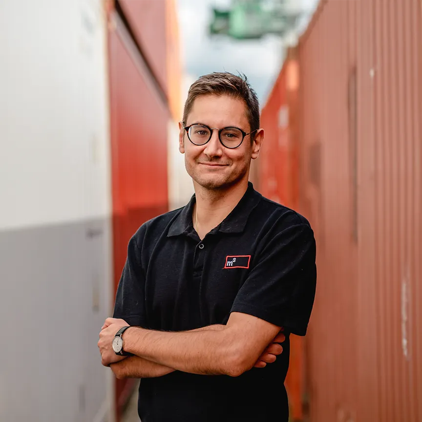Mitarbeiter posiert vor einem Container