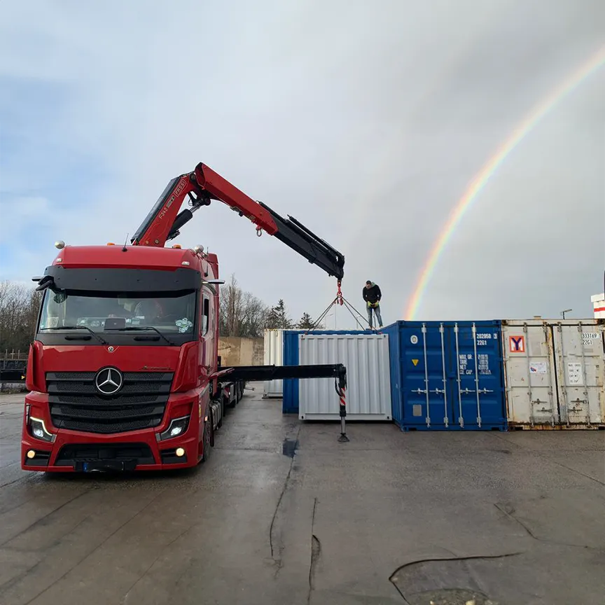 LKW mit Kranarm der Container ablädt