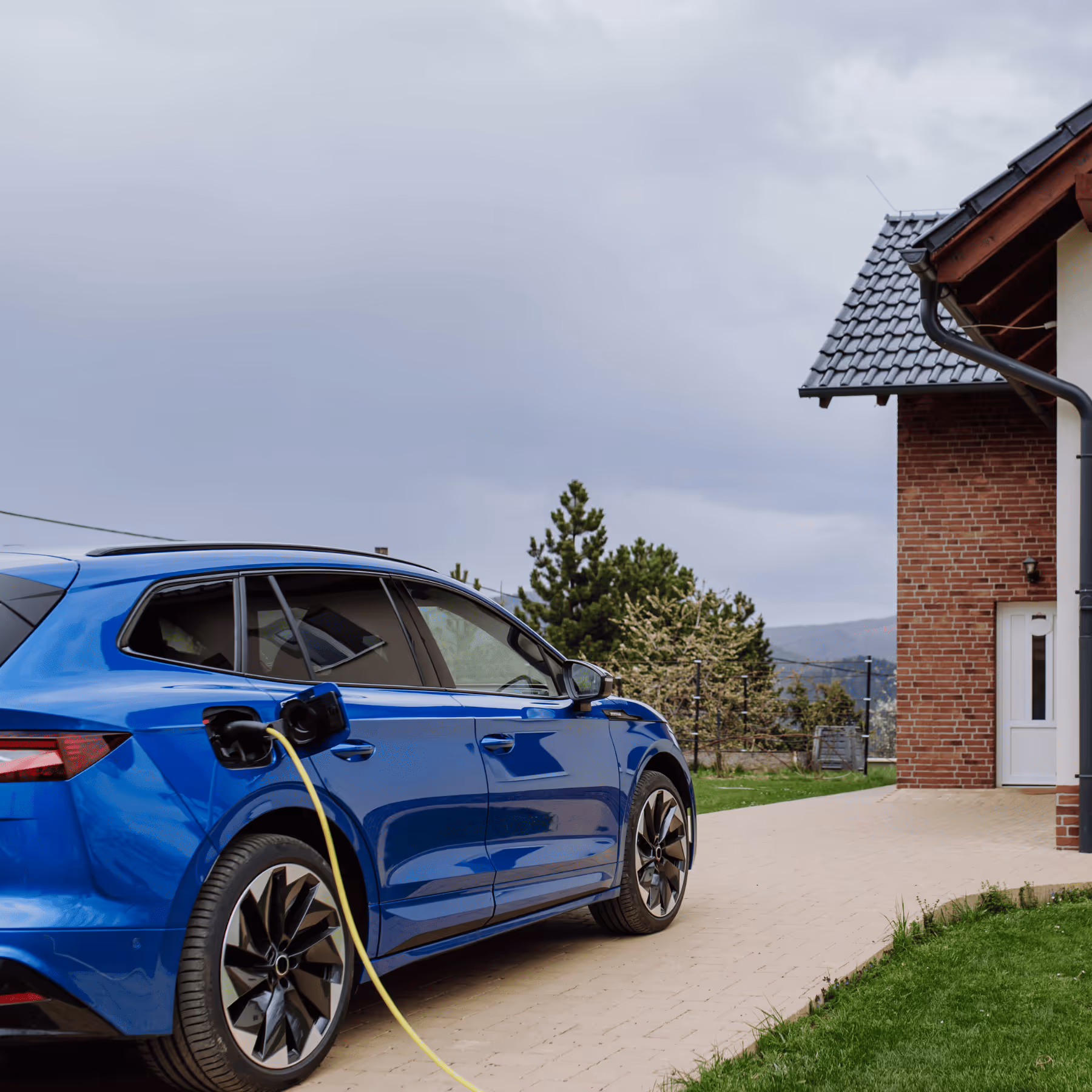 a blue car charging at a house