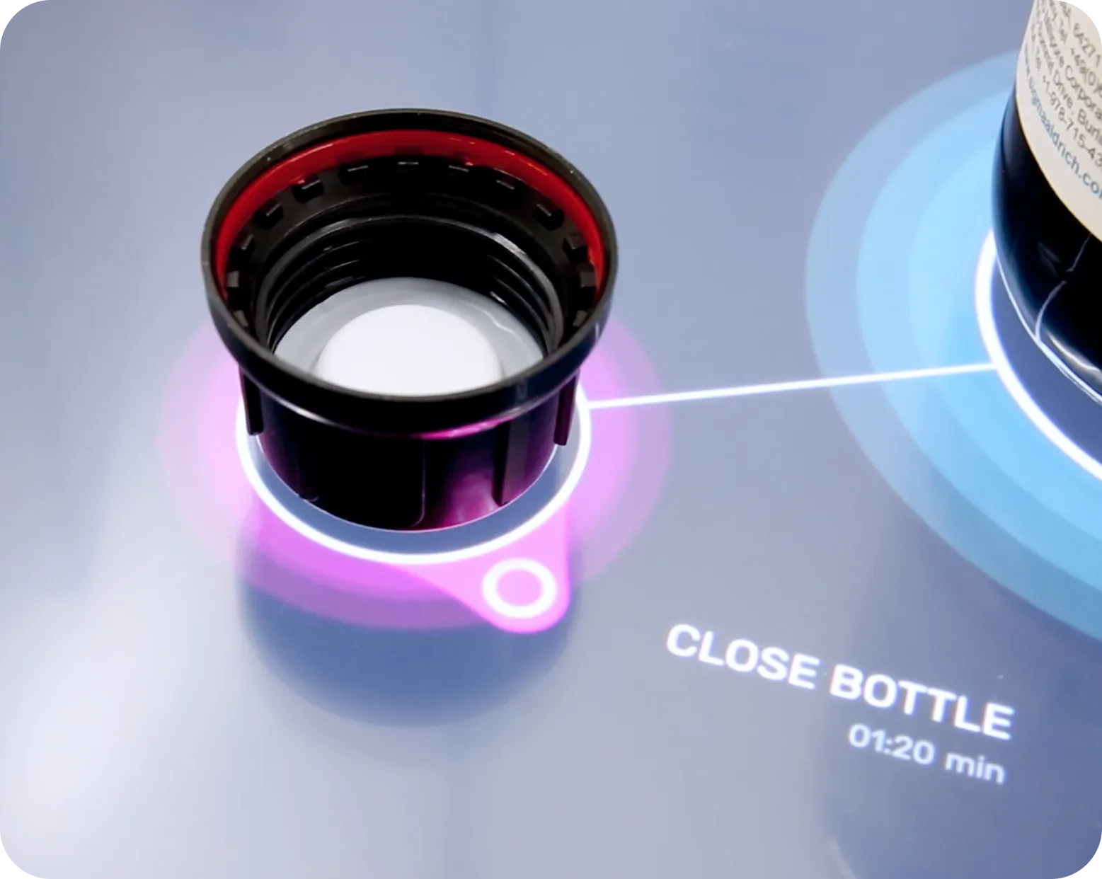 Close-up of a black bottle cap on a glossy surface with digital text reading 'CLOSE BOTTLE 01:20 min' nearby.