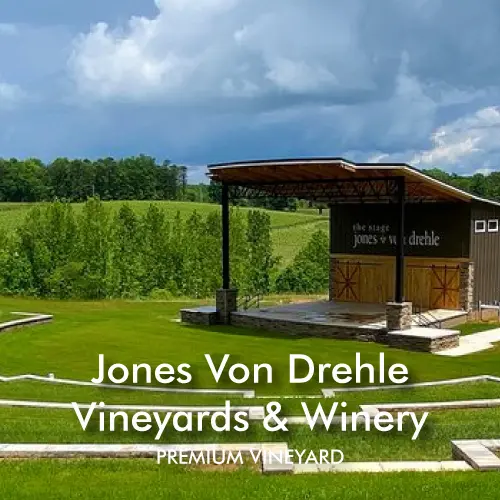 Modern tasting room building at Jones Von Drehle Vineyards & Winery with vineyard rows and cloudy skies in the background.