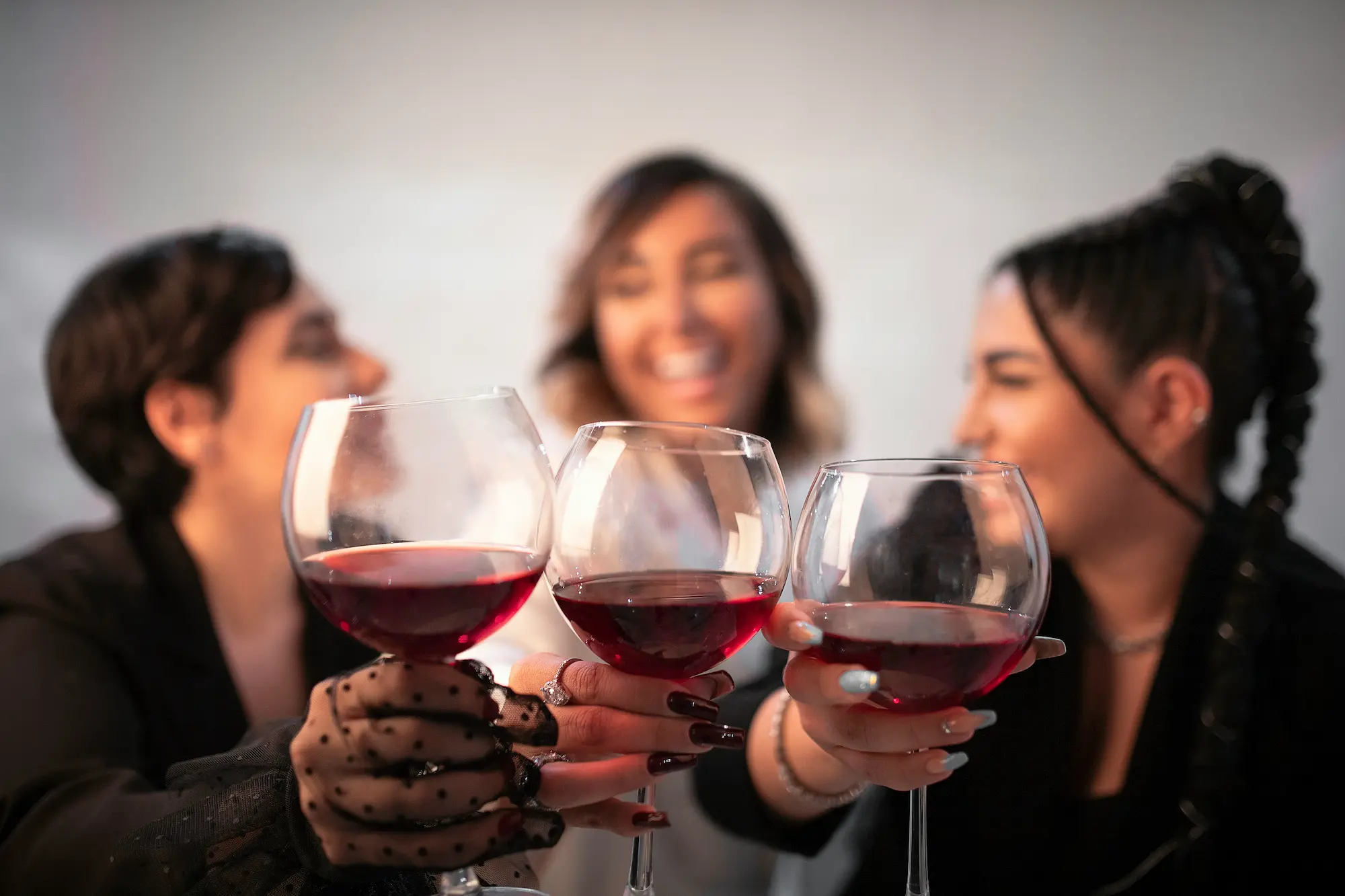 Three women raising their wine glasses in a toast, smiling and enjoying each other's company.