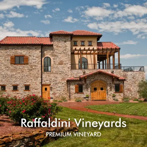 Stone villa estate at Raffaldini Vineyards with terracotta roof and manicured green lawn under dramatic cloudy sky.
