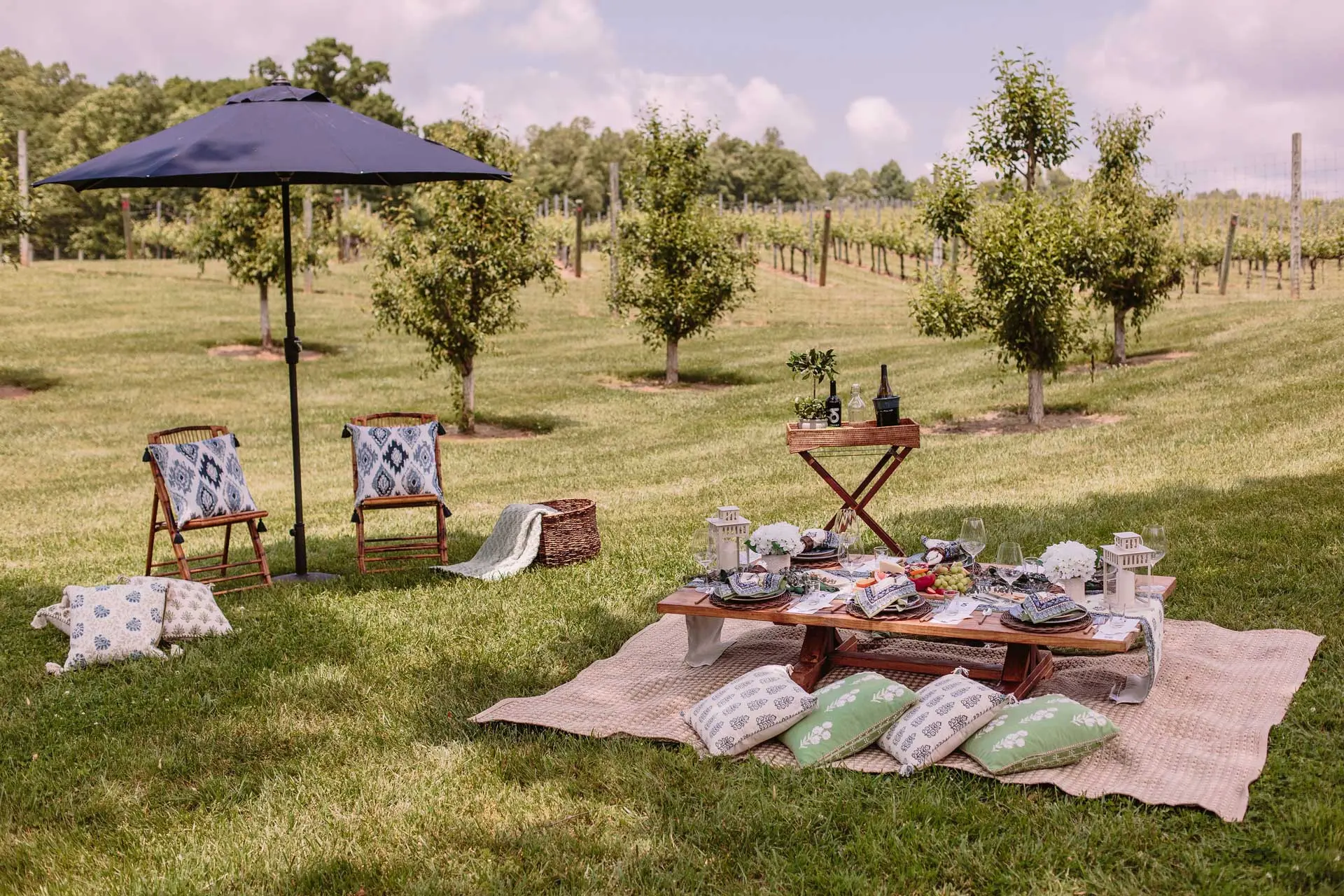 A picnic table with chairs and colorful umbrellas, placed on a grassy lawn, perfect for enjoying meals outdoors.