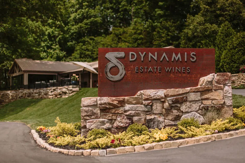 Entrance sign for Dynamis Vineyards surrounded by landscaped greenery.
