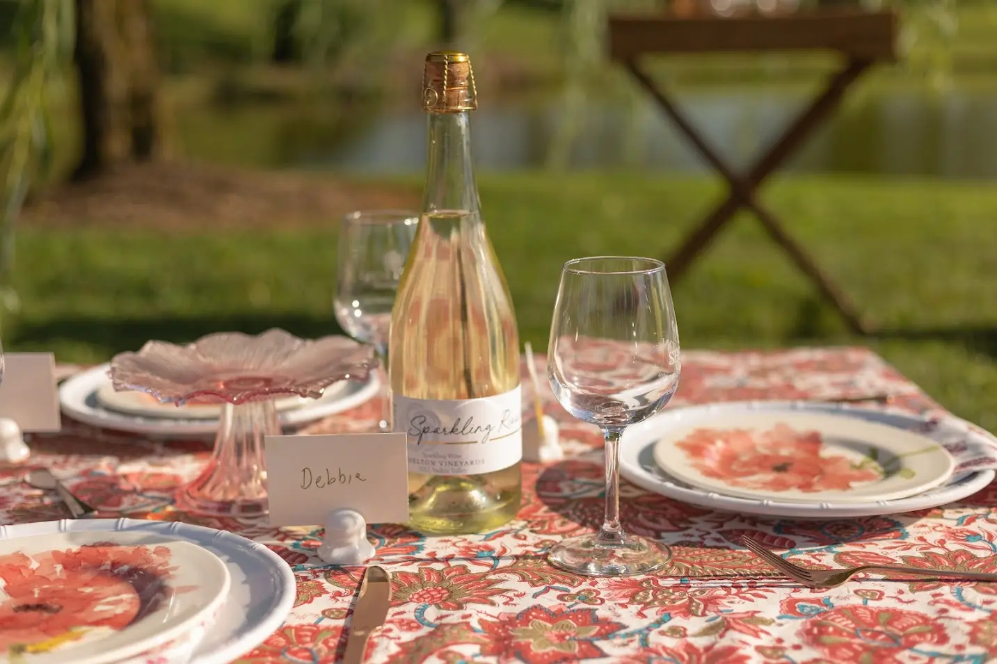 Close-up of vineyard picnic table with pink-patterned tablecloth, glassware, and simple floral centerpiece.