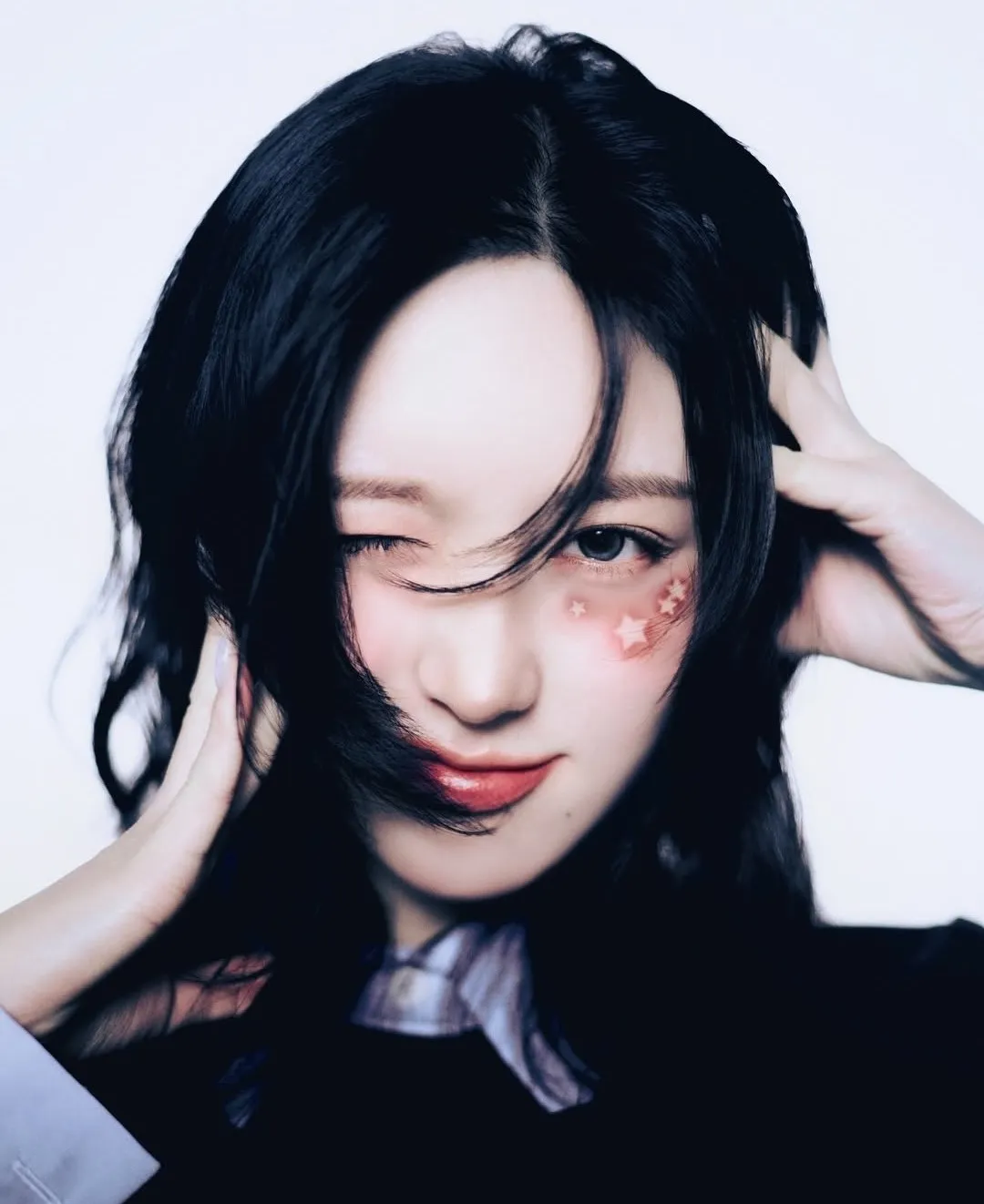 K-pop idol winking with star-shaped face stickers and tousled hair partially covering one eye.