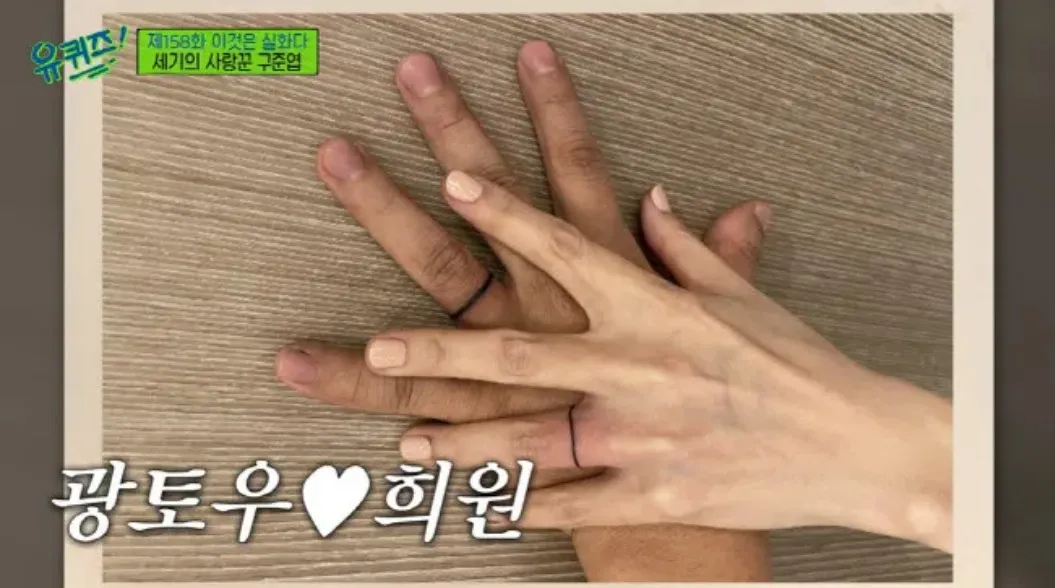 Close-up of a couple's hands with matching tattoo rings on their ring fingers, symbolizing unity and love.