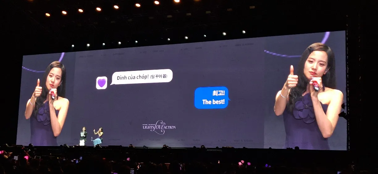 Large screen showing performer giving thumbs up at concert event