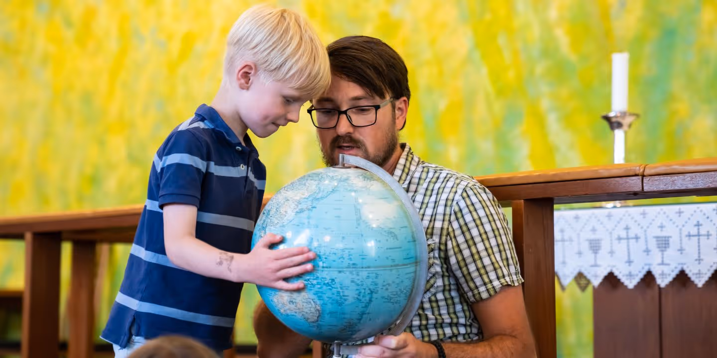 Barn og voksen ser på en globus