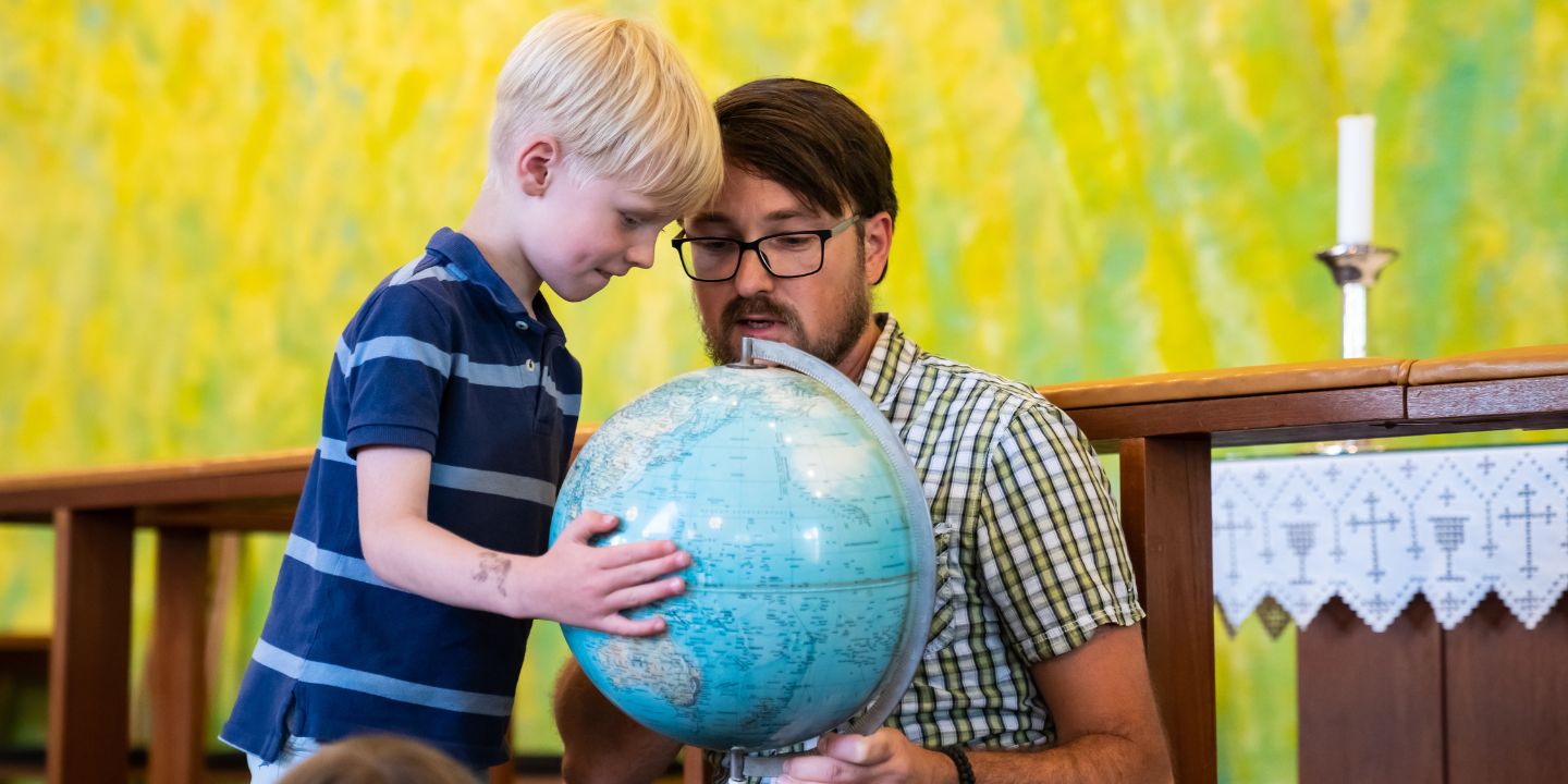 Et barn og en voksen som ser på en globus.